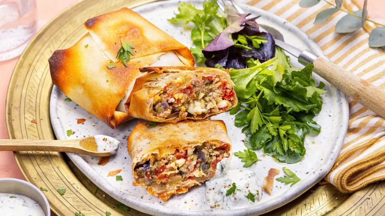 Deux bricks au thon croustillantes, garnies d'une farce savoureuse, servies avec une salade fraîche et une sauce crémeuse.