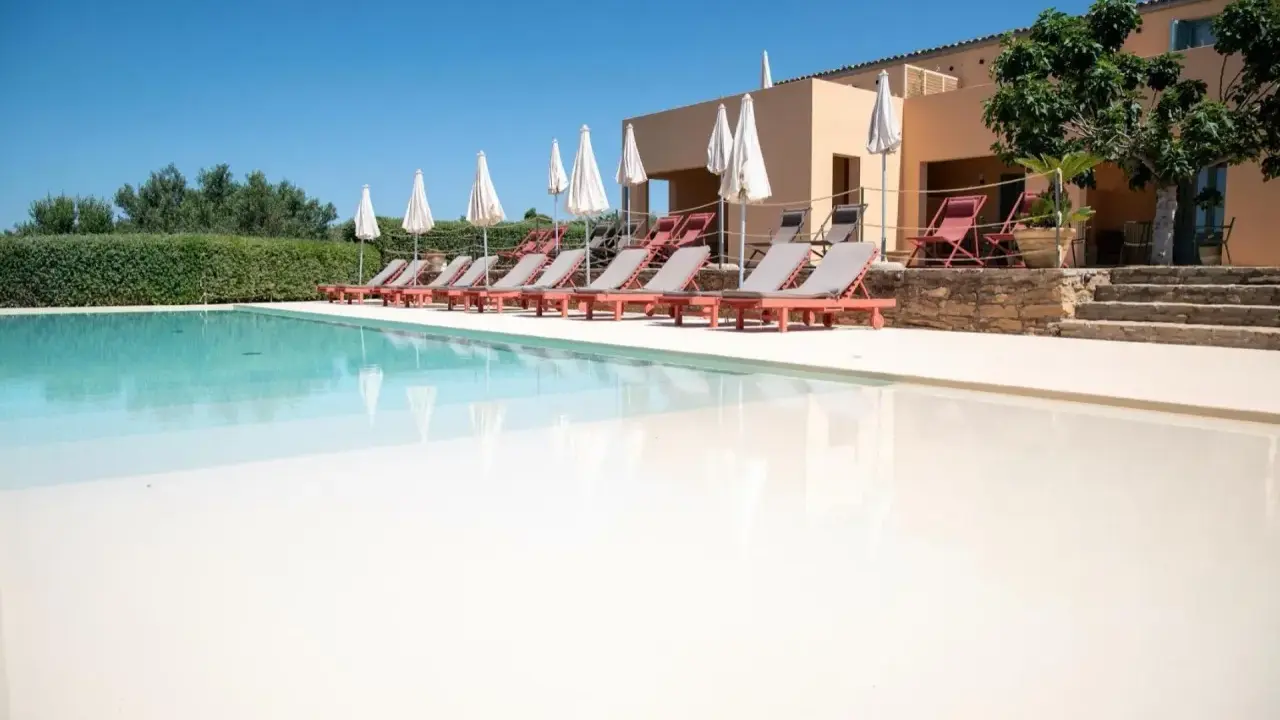 Agriturismi con piscina: lettini prendisole e ombrelloni invitano al relax in un contesto rurale.