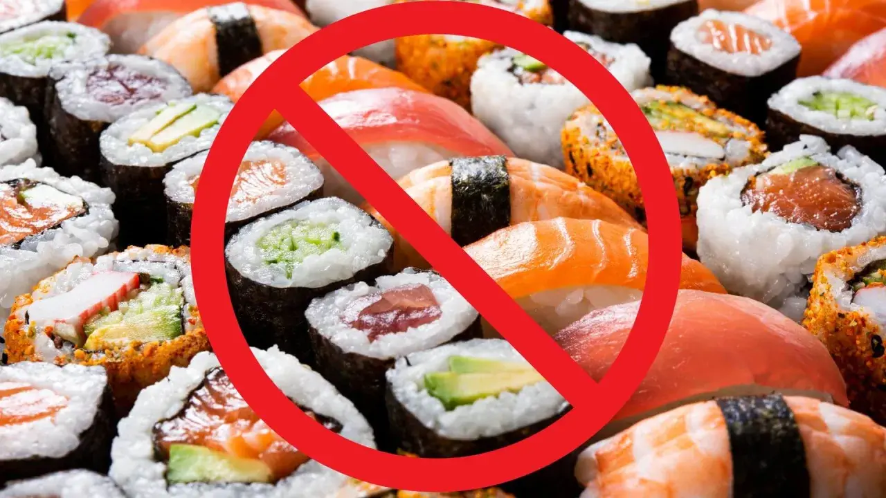 Rotes Verbotsschild über Sushi und Maki-Rollen. Achtung: verbotene Lebensmittel Schwangerschaft.
