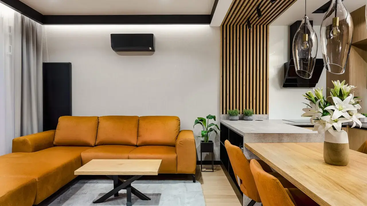 Nowoczesny salon bez sufitu z pomarańczową kanapą, drewnianym stołem i designerskimi lampami.