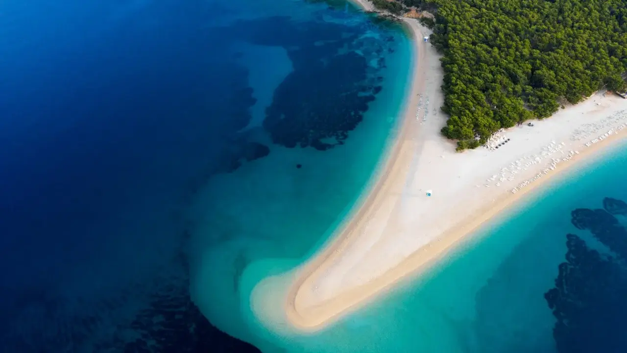 Widok z lotu ptaka na Zlatni Rat w Chorwacji. Plaże otoczone turkusowym morzem i zielonym lasem.