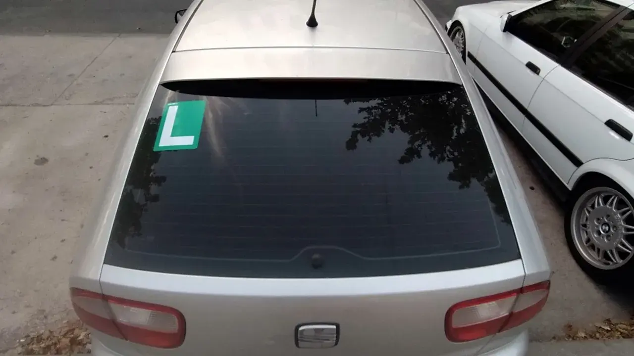 El coche plateado tiene una L verde en el lado izquierdo de la ventana trasera, indicando que el conductor está aprendiendo.