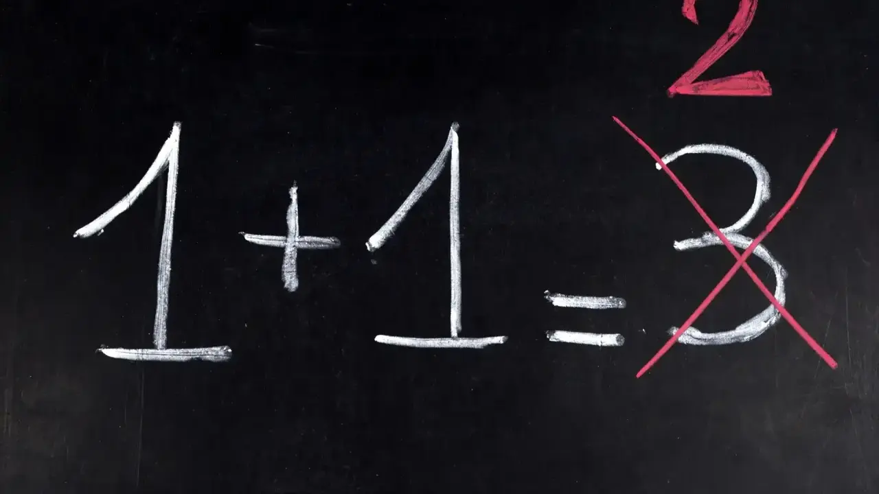 Na czarnej tablicy napisano kredą: 1+1=2. Liczba 3 jest przekreślona, jakby to był trudny egzamin dojrzałości.