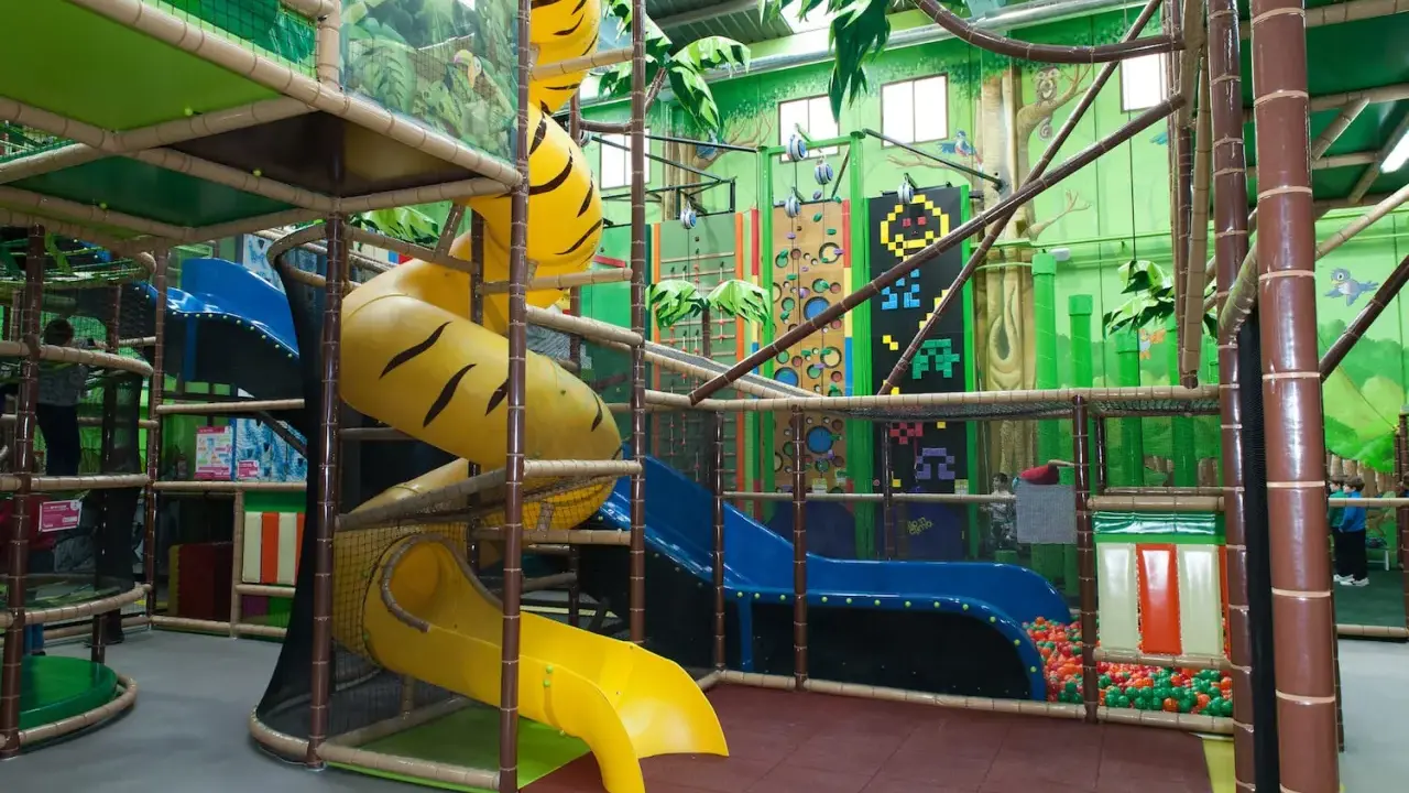 Un divertido parque infantil en Madrid con toboganes amarillos y azules, rocódromos y una piscina de bolas.
