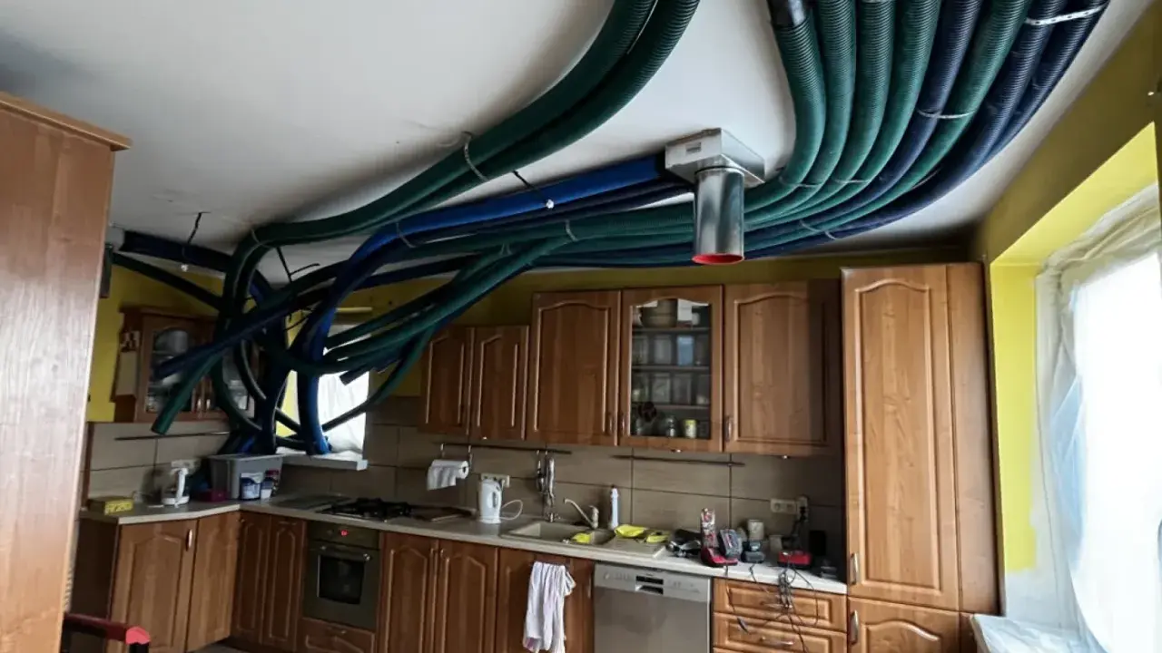 Instalacja rekuperacji w starym domu. W kuchni na suficie widać gęstą sieć zielonych i niebieskich rur wentylacyjnych.