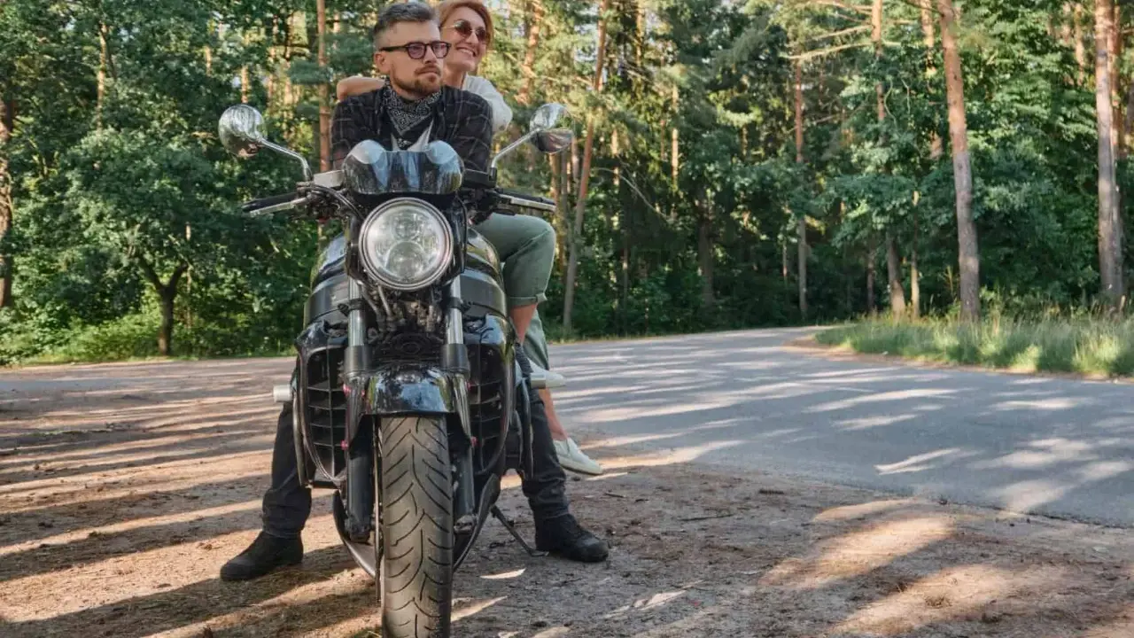 Para na motocyklu, ciesząca się słońcem i lasem podczas podróży motocyklem po Polsce.