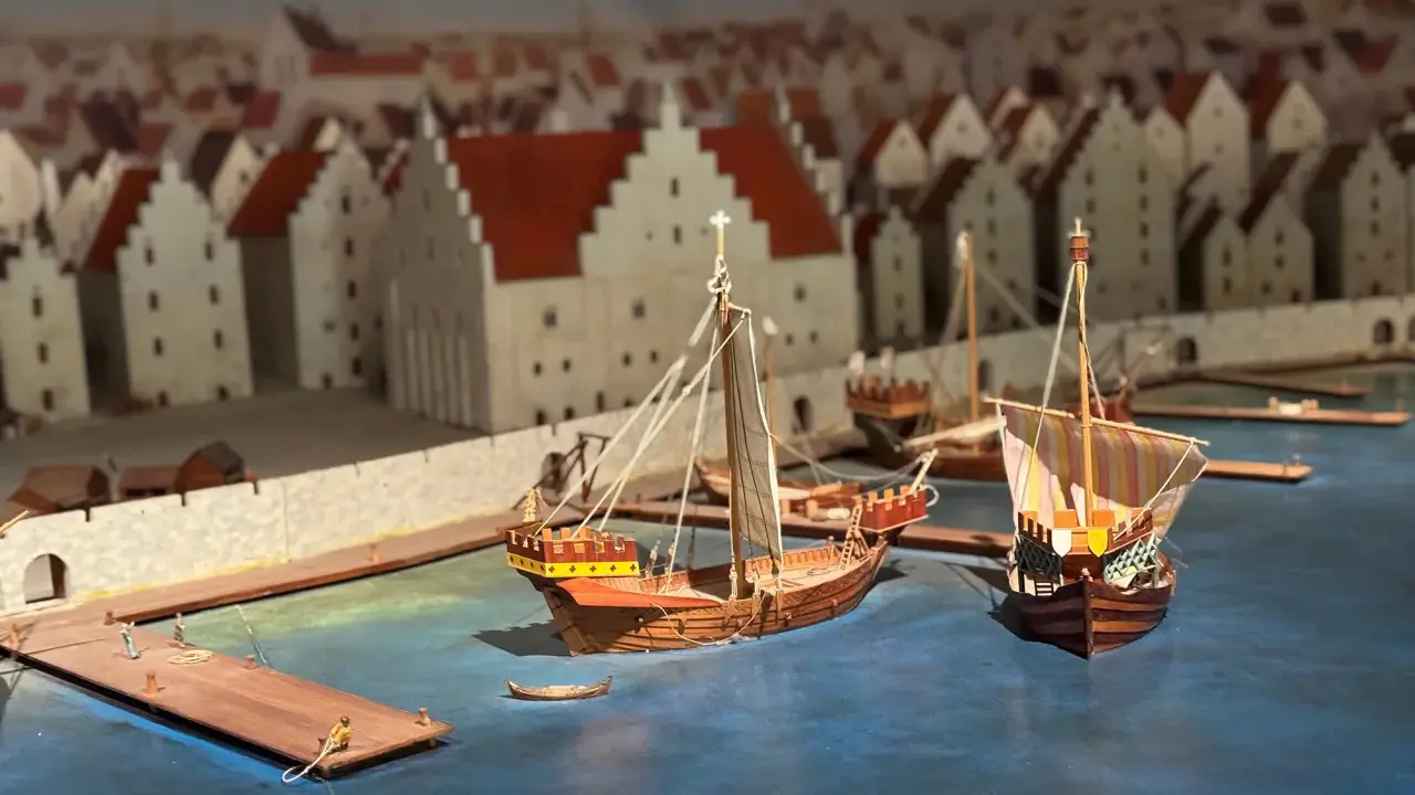 Modell av medeltida hamn i Visby. Skepp ligger vid kajen framför stadens karaktäristiska hus. En glimt av Visby historia.