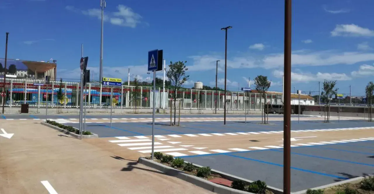 Parcheggio rimini con strisce pedonali e segnaletica, sullo sfondo un treno blu.