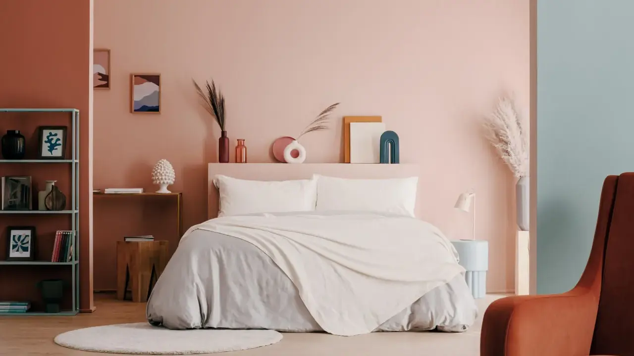 Camera da letto con pareti rosa e turchesi, un letto accogliente e decorazioni che evocano i colori della cromoterapia.