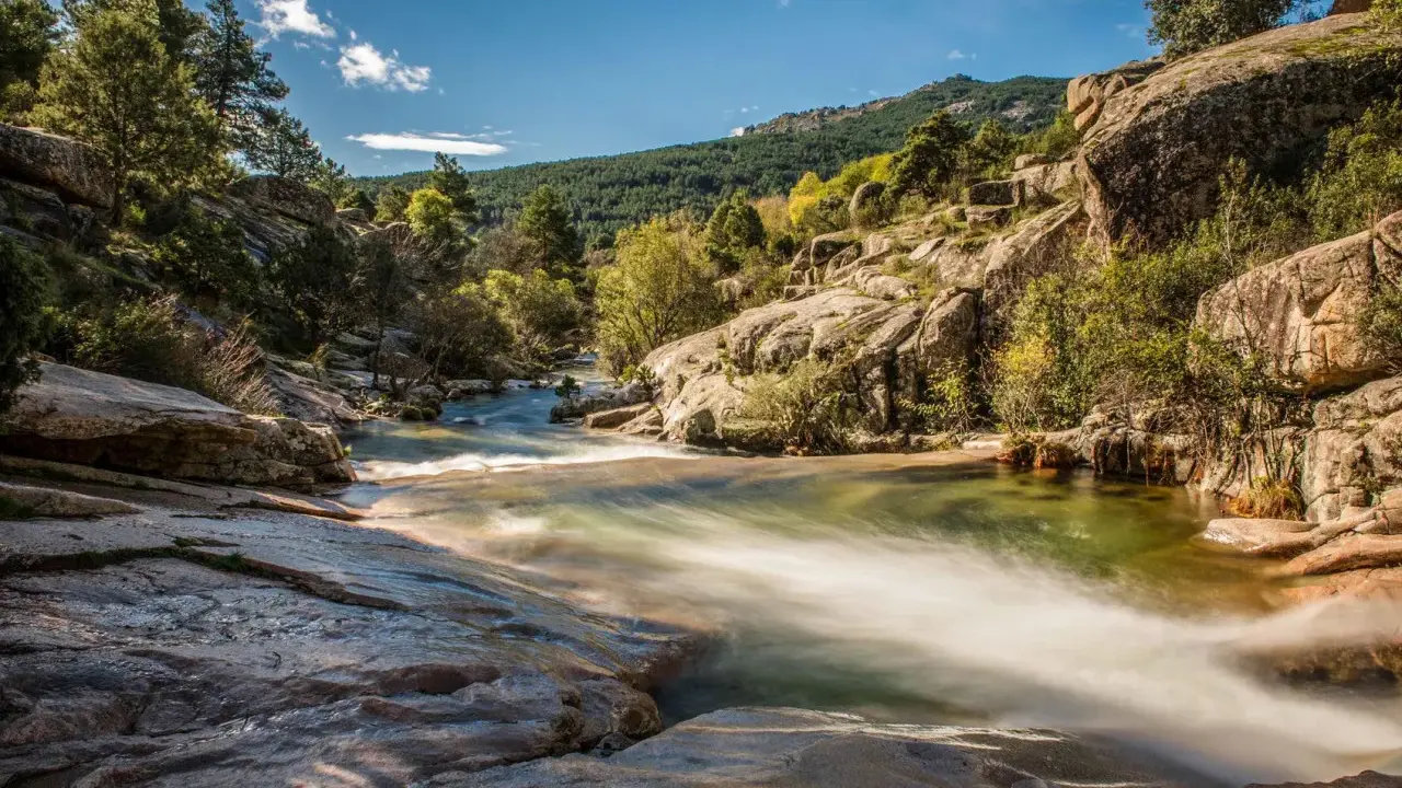 Río serpenteante entre rocas y vegetación, ideal para excursiones cerca de Madrid. Un paisaje natural de ensueño.