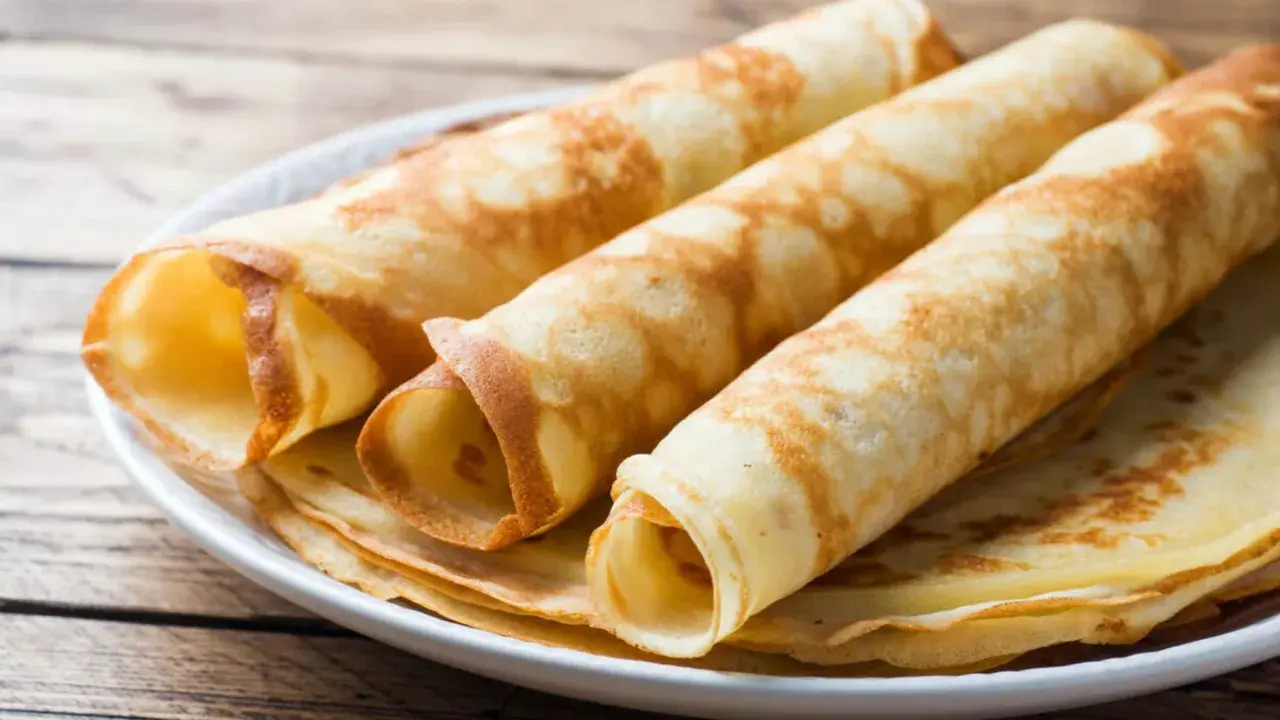 Gestapelte, gerollte Pfannkuchen ohne Mehl auf einem Teller. Sie sind goldbraun und sehen lecker aus.