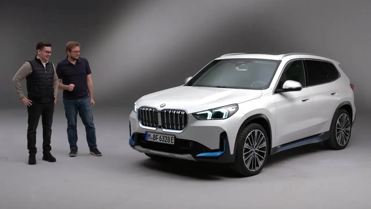 Dwóch mężczyzn stoi obok białego BMW iX1.