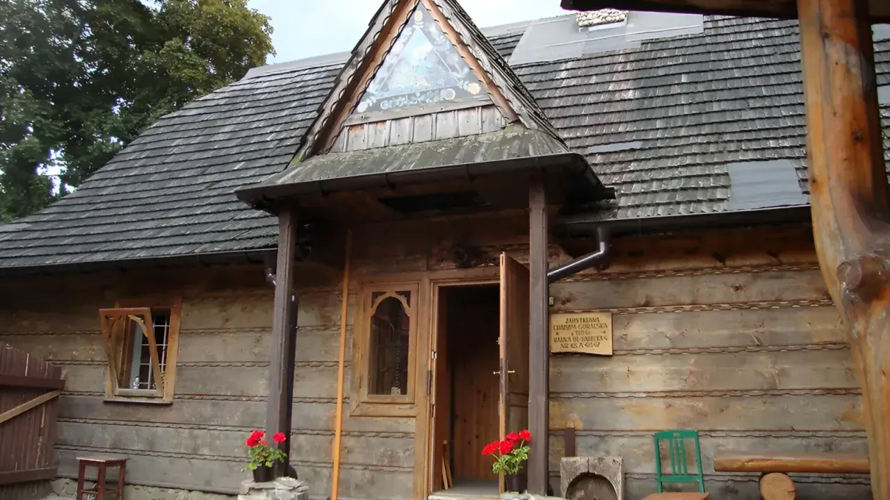 Drewniany budynek muzeum górali i zbójników z charakterystycznym trójkątnym okienkiem nad wejściem.