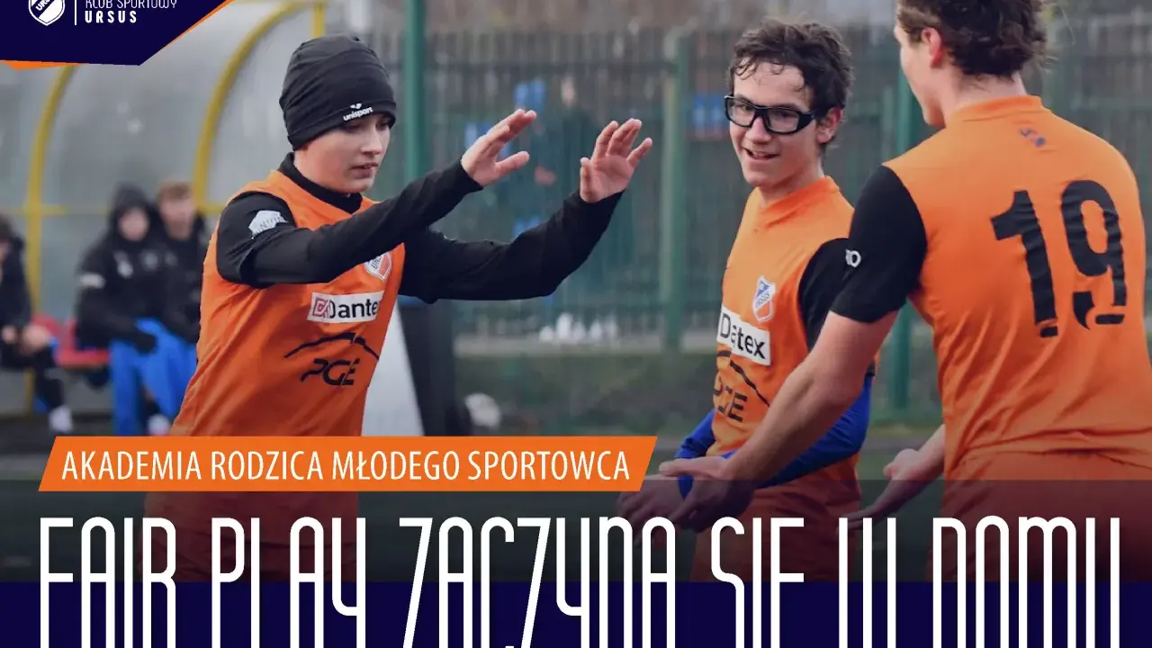 Trzech młodych piłkarzy w pomarańczowych koszulkach świętuje na boisku. Napis głosi: "Fair play zaczyna się w domu".