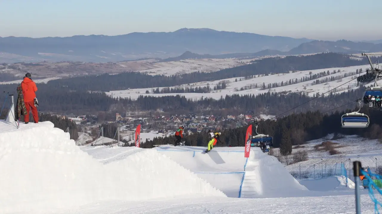 Snowboardziści na stoku, idealne miejsce, gdzie na narty z Wrocławia. W tle góry i miasteczko.