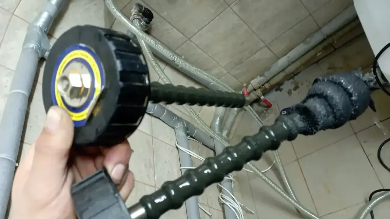 Przygotowanie do czyszczenia instalacji co: ręka trzyma sondę z głowicą do inspekcji rur.