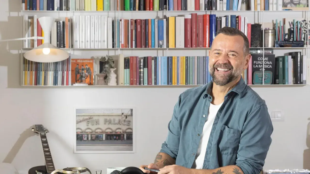 Fabio Volo sorride tra gli scaffali pieni di libri, forse in attesa di presentare il suo ultimo libro.