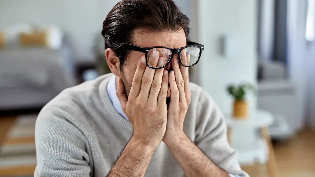 Mann mit Brille reibt sich die Augen, wirkt gestresst. Manche glauben, rauchen hilft gegen Stress, doch das ist ein Trugschluss.