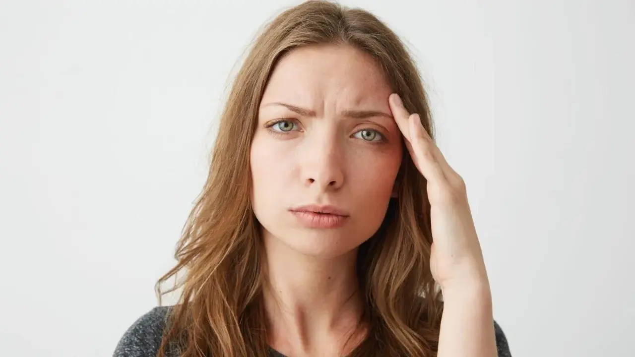 Donna con mano sulla tempia, espressione preoccupata, forse per lo stress ossidativo della pelle.