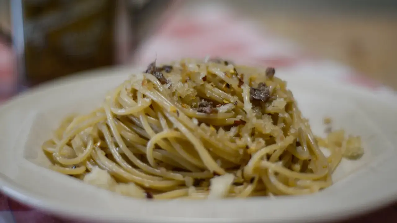 Un piatto di spaghetti conditi con pangrattato tostato, aglio, peperoncino e formaggio grattugiato, un classico della pasta mollicata.