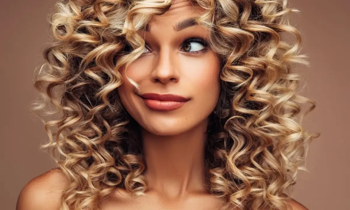 Kobieta z burzą blond loków do ramion. Jej fryzury włosy kręcone do ramion dodają jej uroku i pewności siebie.