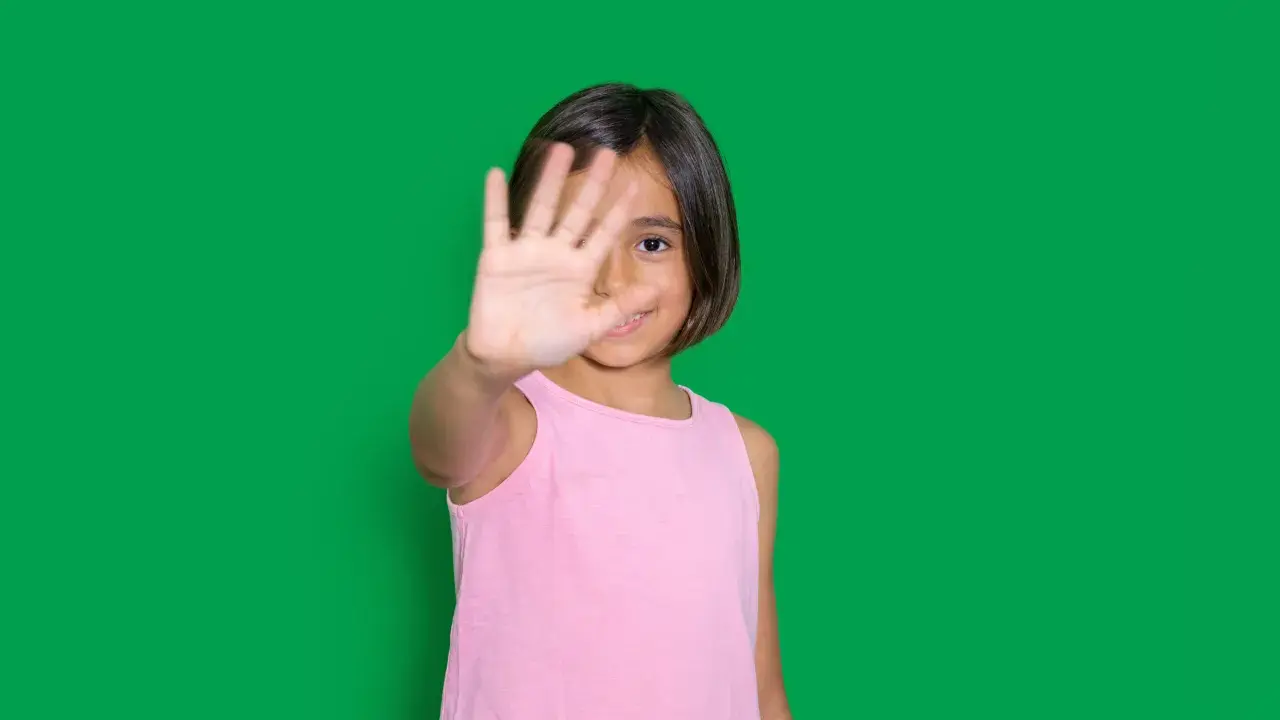 Niña de 4-5 años muestra timidez en niños, cubriendo su rostro con la mano.