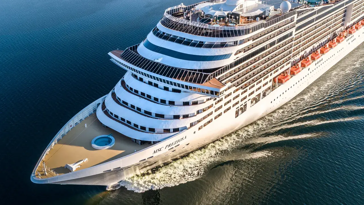 La MSC Preziosa solca il mare blu. L'equipaggio nave da crociera si prepara per un nuovo viaggio, con le scialuppe di salvataggio pronte.