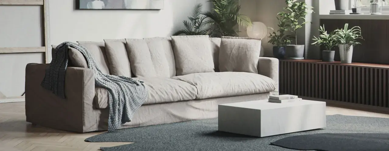 En bekväm soffa med nedsuttna dynor, prydd med en stickad pläd. Framför står ett lågt, vitt soffbord.