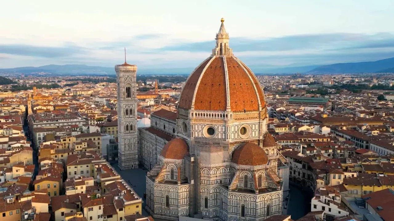 Vue aérienne de la **cattedrale Santa Maria** del Fiore et de son campanile, dominant les toits de Florence au lever du soleil.