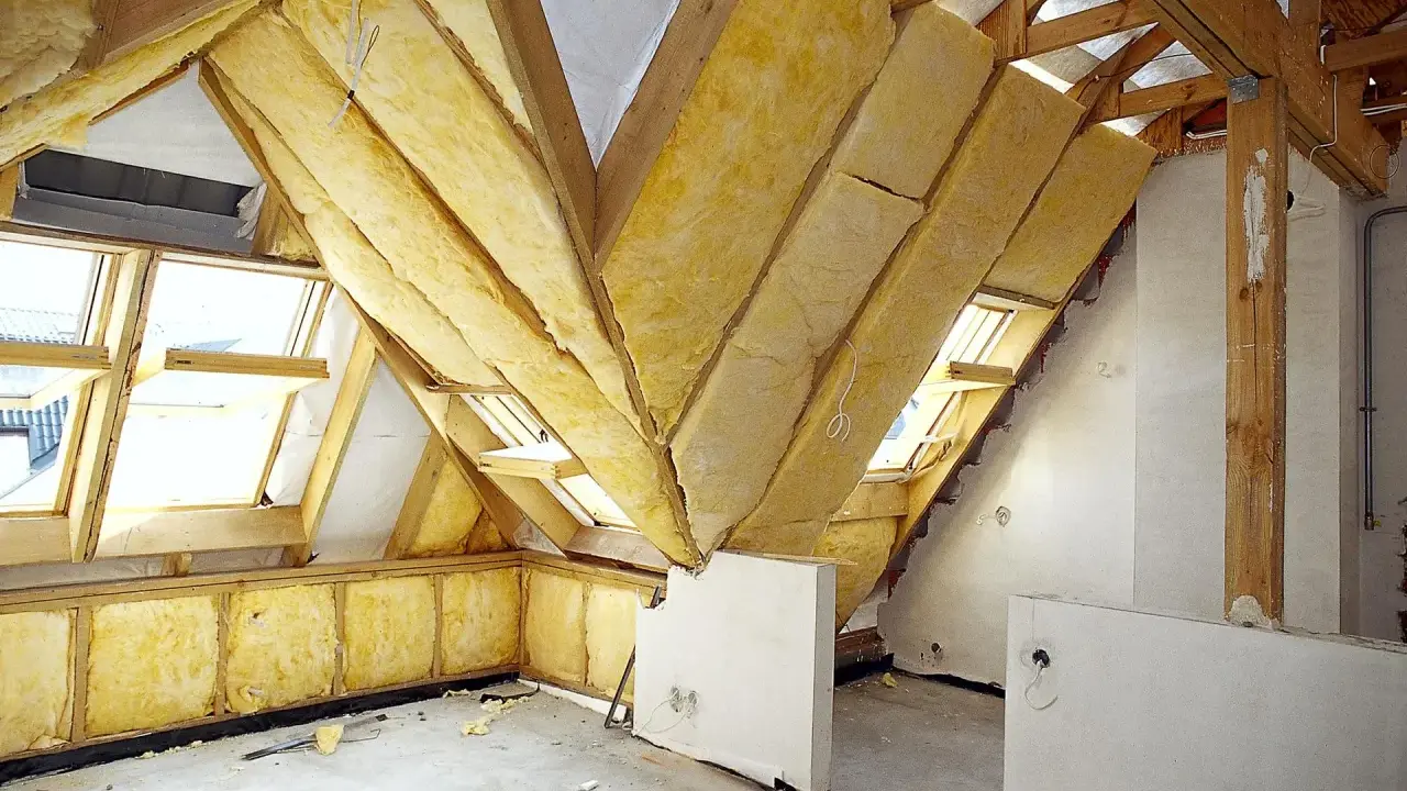 Trwa adaptacja poddasza. Widoczne drewniane konstrukcje, wełna mineralna jako izolacja i okna dachowe.