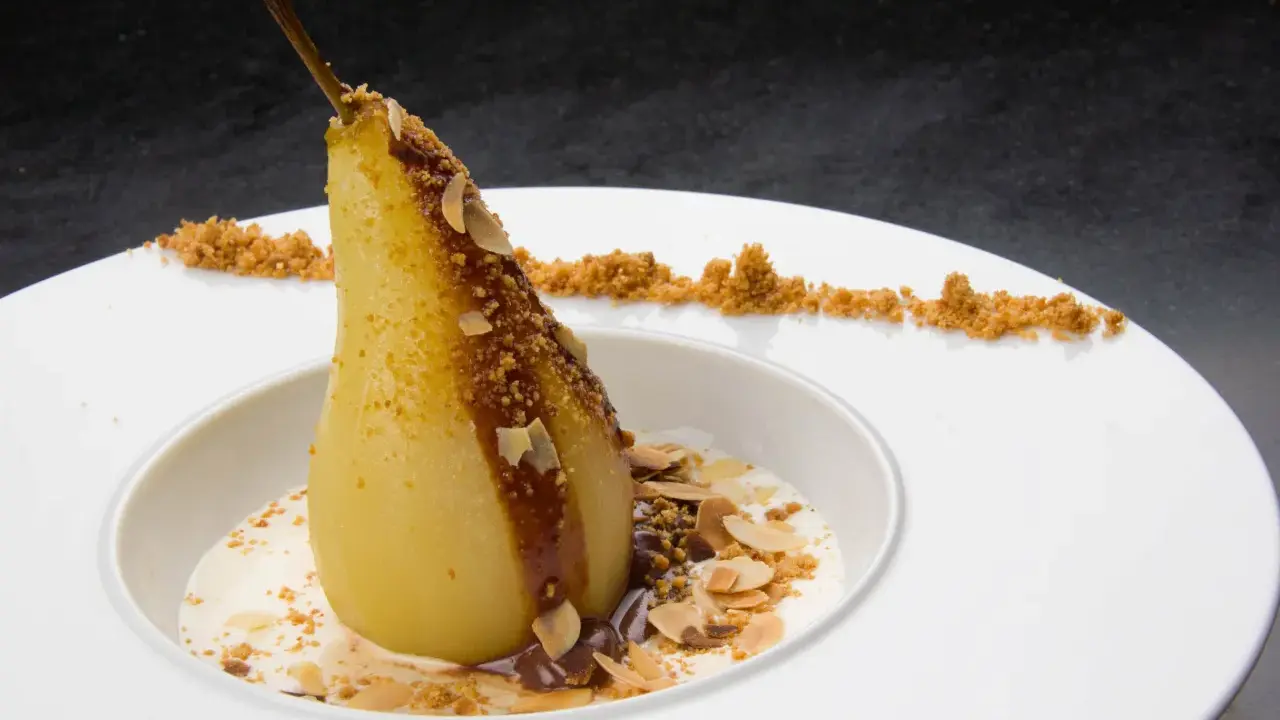 Un poire pochée, nappée de chocolat et amandes effilées, servie avec une crème légère. Un dessert poire chocolat rapide et gourmand.