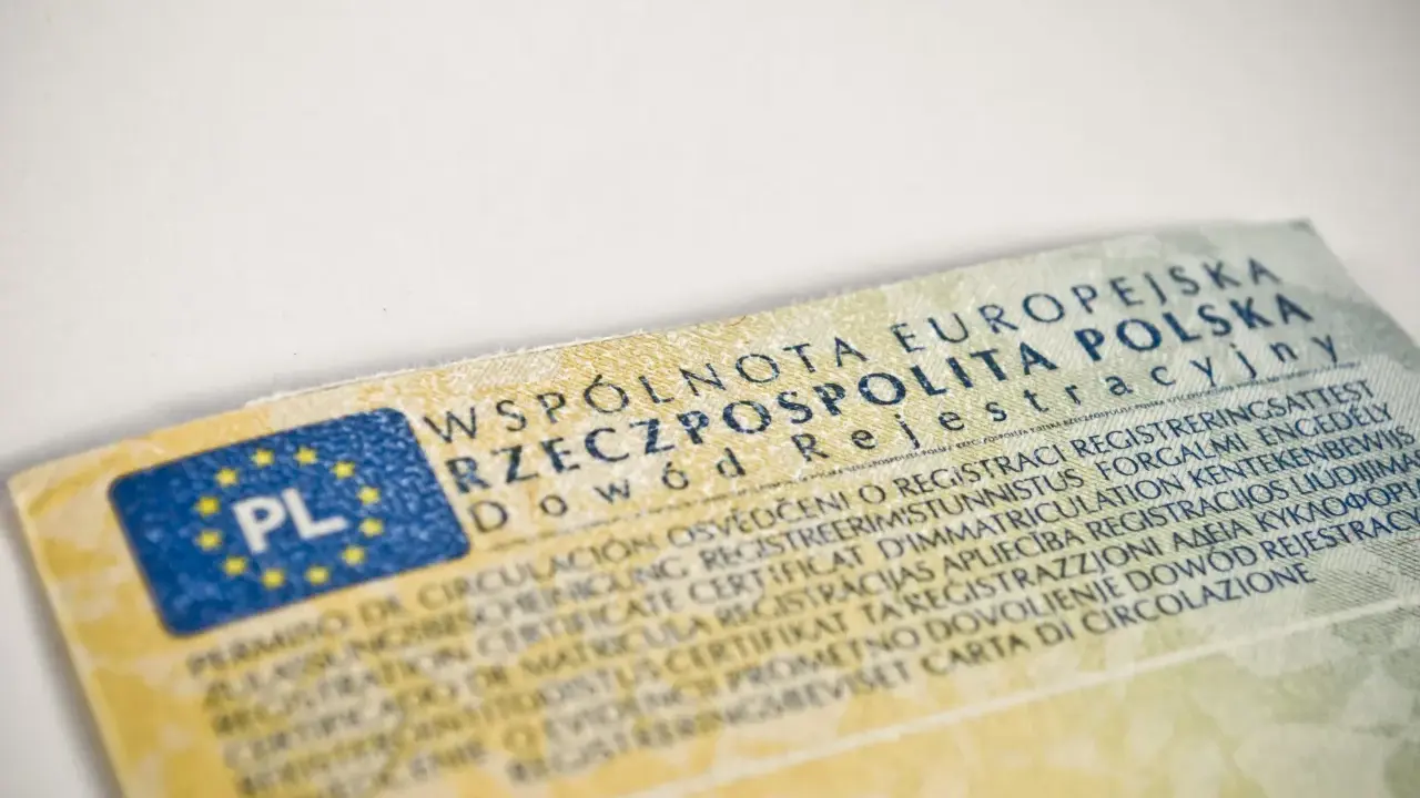 Dowód rejestracyjny pojazdu, niezbędny do ubezpieczenia samochodu, z flagą PL i tekstem w wielu językach.