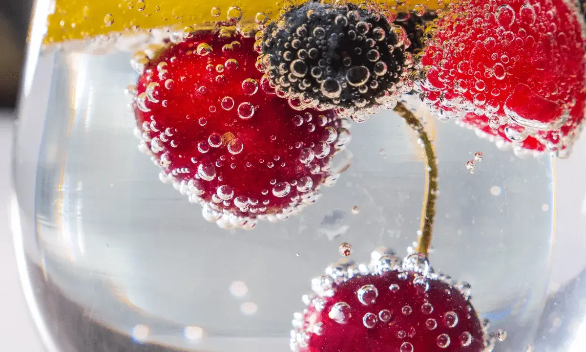 Erfrischendes Getränk mit Kirschen, Blaubeeren und Zitrone in sprudelndem Wasser. Der Unterschied Sodawasser und Mineralwasser liegt in der Kohlensäure.