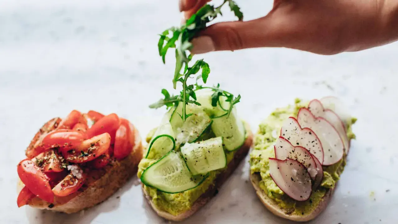 Tres tostadas gourmet: tomate, pepino y aguacate con rábano. La mejor variedad de aceite de oliva para tostadas realza sus sabores.