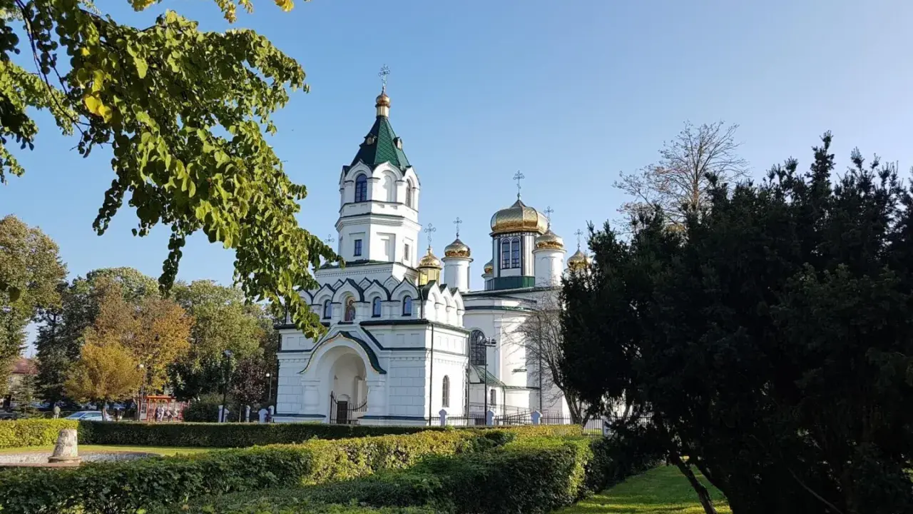 Biała cerkiew ze złotymi kopułami, otoczona zielenią. Piękny widok na szlak tatarski w słoneczny dzień.