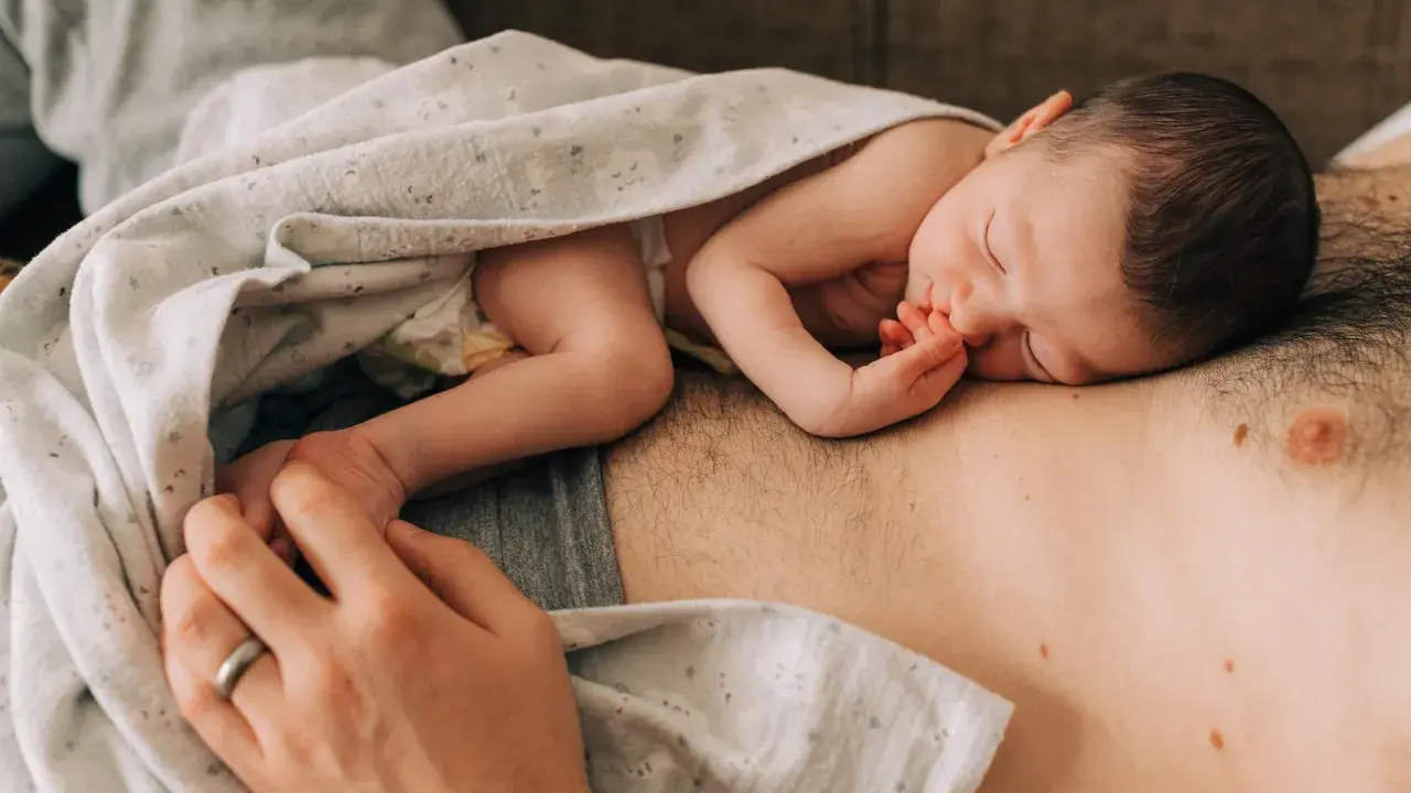 Ein Neugeborenes schläft auf der Brust seines Vaters. Die Frage "wie werde ich ein guter vater" wird hier durch diese liebevolle Szene beantwortet.