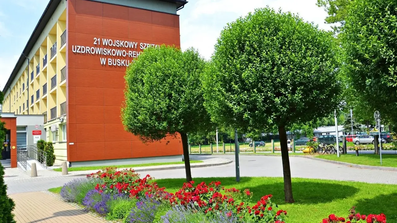 Sanatorium MSW Busko Zdrój z czerwonymi różami i lawendą w słoneczny dzień.