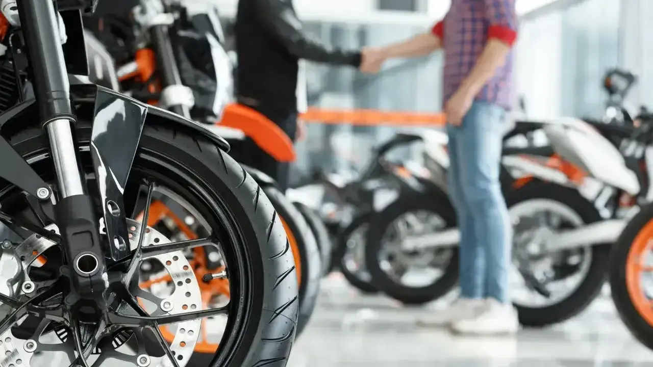 Dwóch mężczyzn ściska sobie dłonie przy motocyklach. Sfinalizowali sprzedaż motocykla przed upływem 6 miesięcy.