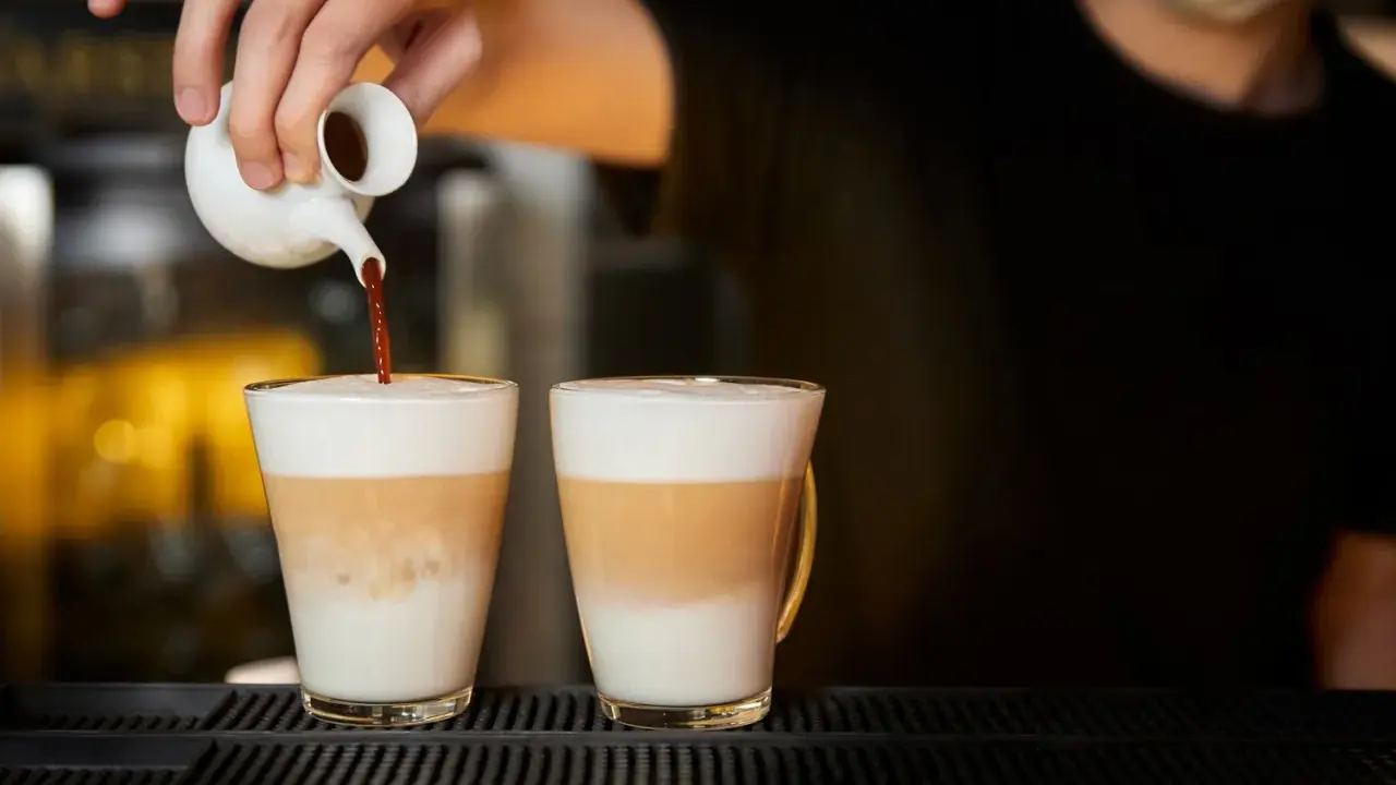 Barista wlewa espresso do dwóch latte macchiato. Zastanawiasz się, ile kcal ma latte macchiato?