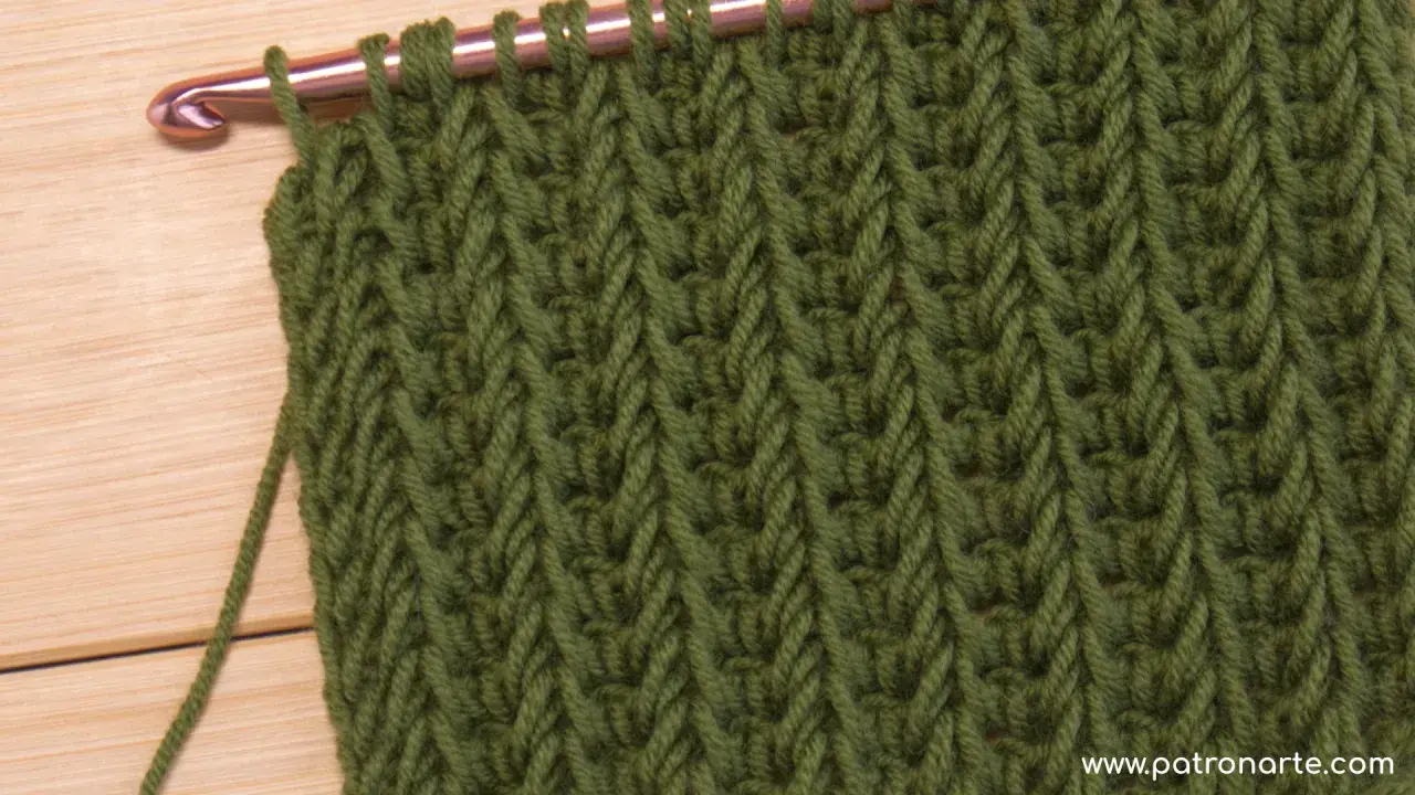 Punto tunecino con ganchillo en verde, ideal para mantas. El patrón crea un tejido denso y texturizado.