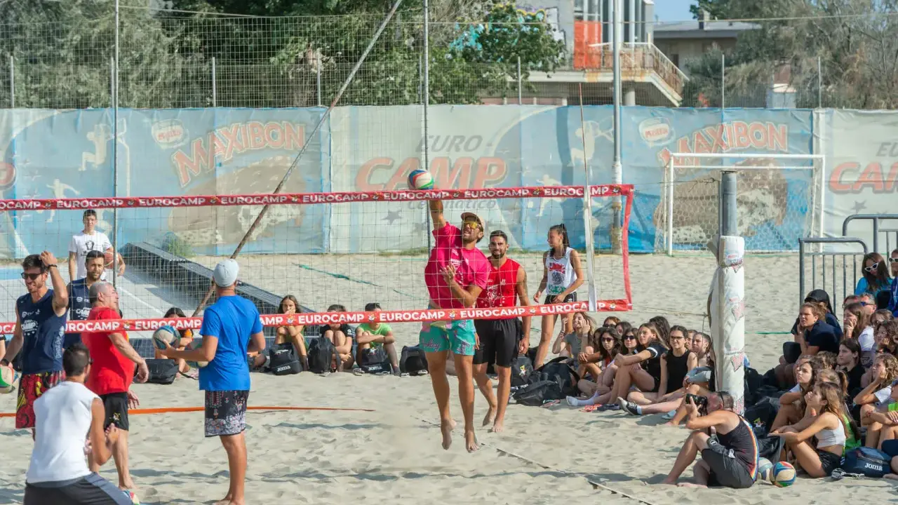 Partita di camp volley Cesenatico: un giocatore salta per colpire la palla mentre gli spettatori osservano.