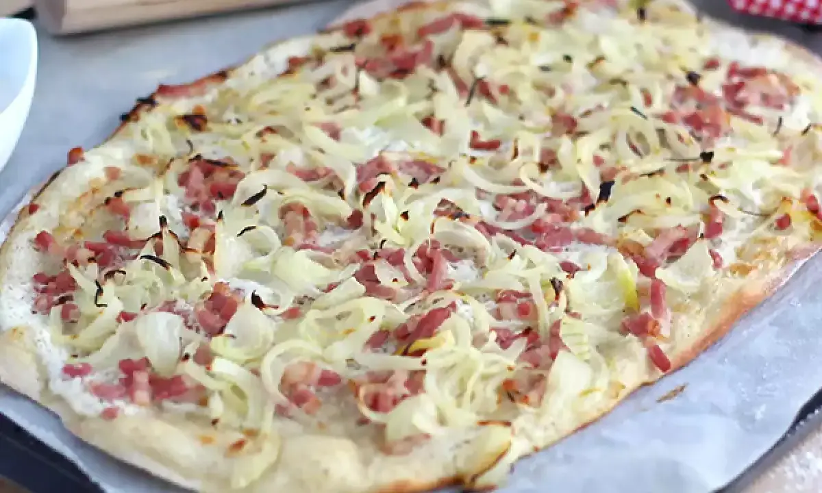Flammekueche croustillante, garnie d'oignons et lardons. La vraie recette flammekueche, prête à être dégustée.