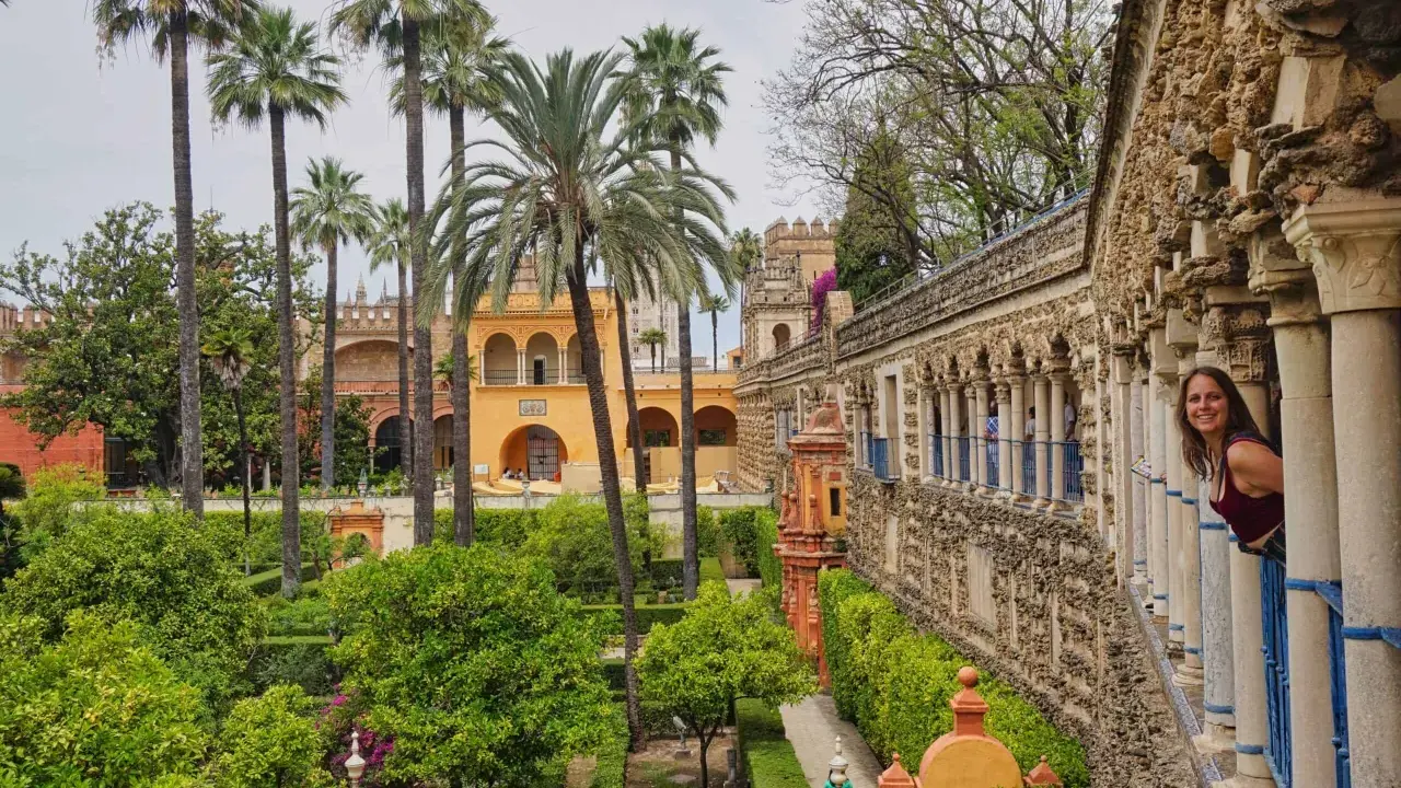 Ein Wahrzeichen von Sevilla: üppige Gärten, Palmen und eine Frau, die aus einem Säulengang schaut.