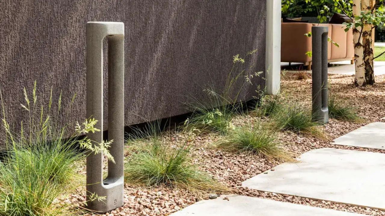 Deux bornes d'éclairage modernes en béton, bordant un chemin. L'ensemble respecte la norme éclairage lux pour un jardin contemporain.