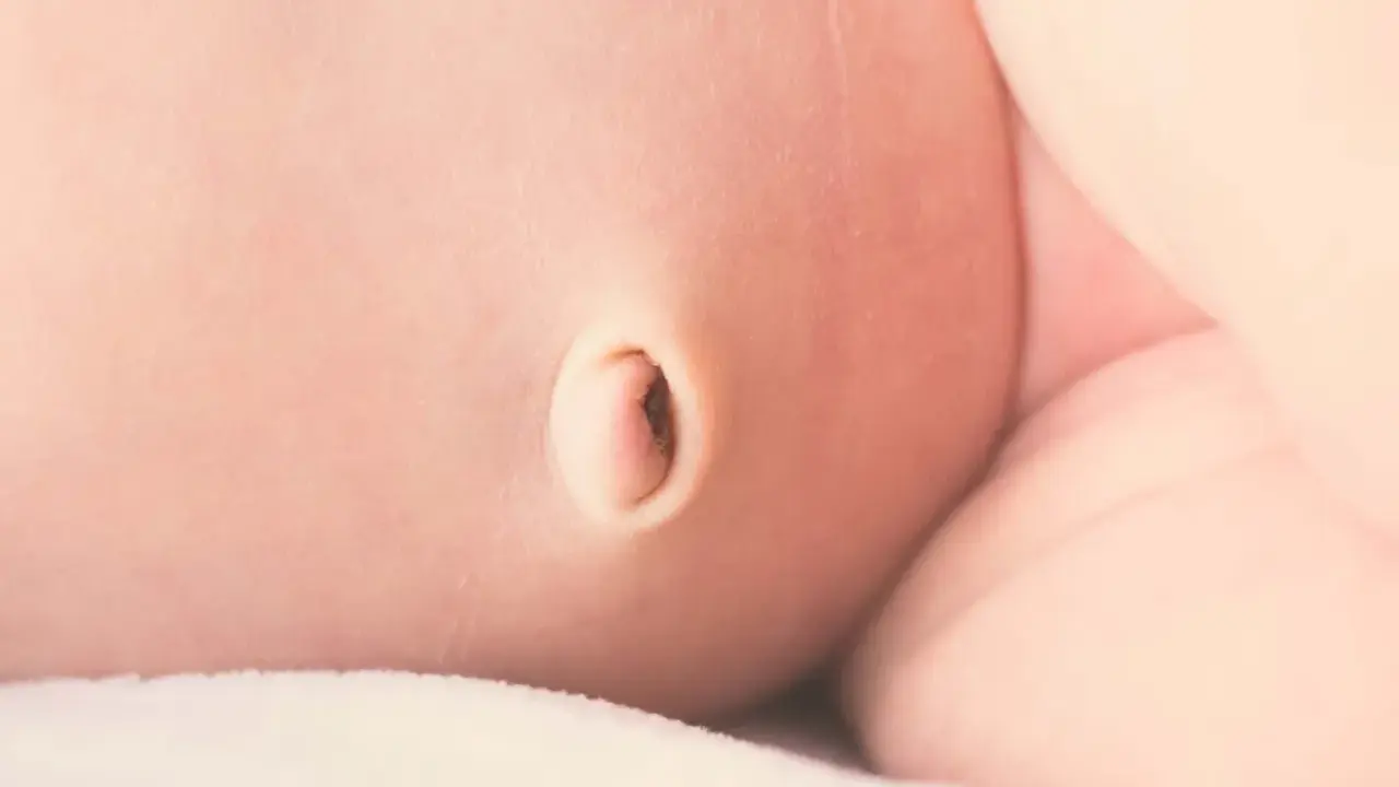 Primer plano de la piel de un bebé, mostrando un ombligo con una leve hernia umbilical.