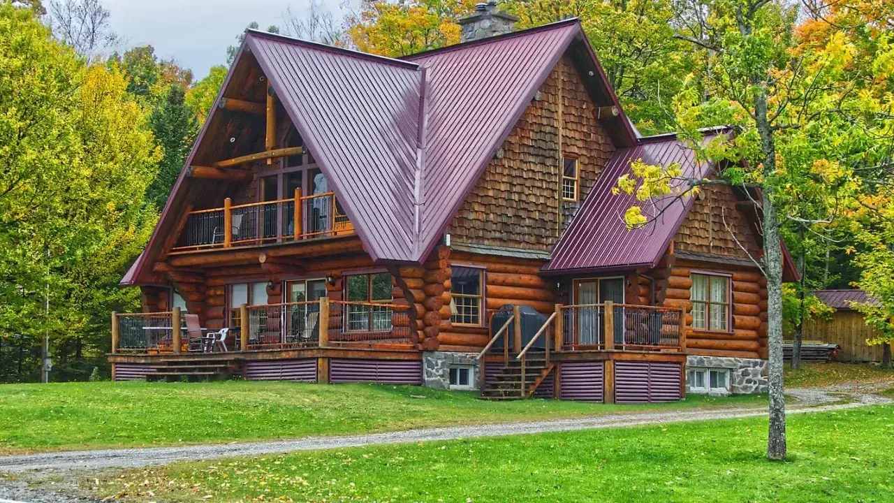 Chalet en bois rond avec toiture métallique, entouré d'arbres aux couleurs d'automne. Un exemple de développement durable bâtiment, alliant esthétique et respect de l'environnement.