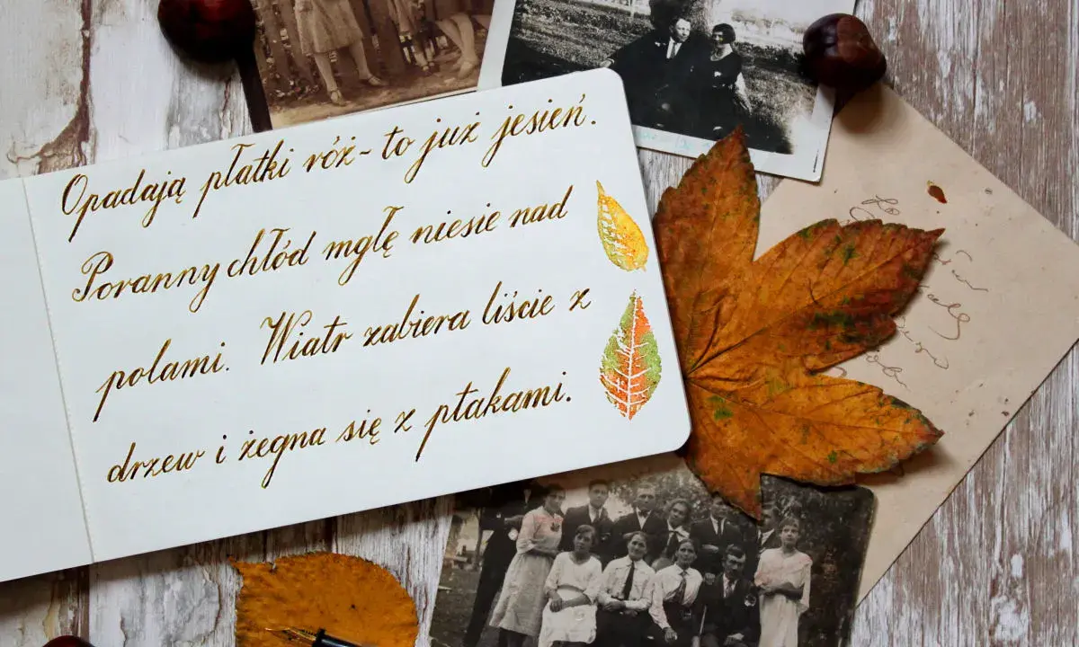 Starodawne pismo na karcie, obok jesienne liście i stare fotografie. Wiatr zabiera liście z drzew, żegnając się z ptakami.