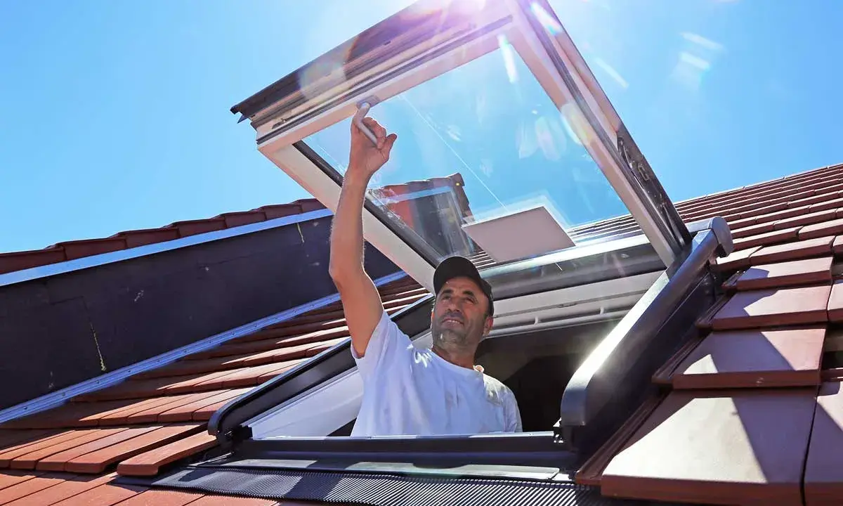 Mann installiert Dachfenster. Informieren Sie sich über Dachfenster Kosten und die Vorteile von mehr Licht.