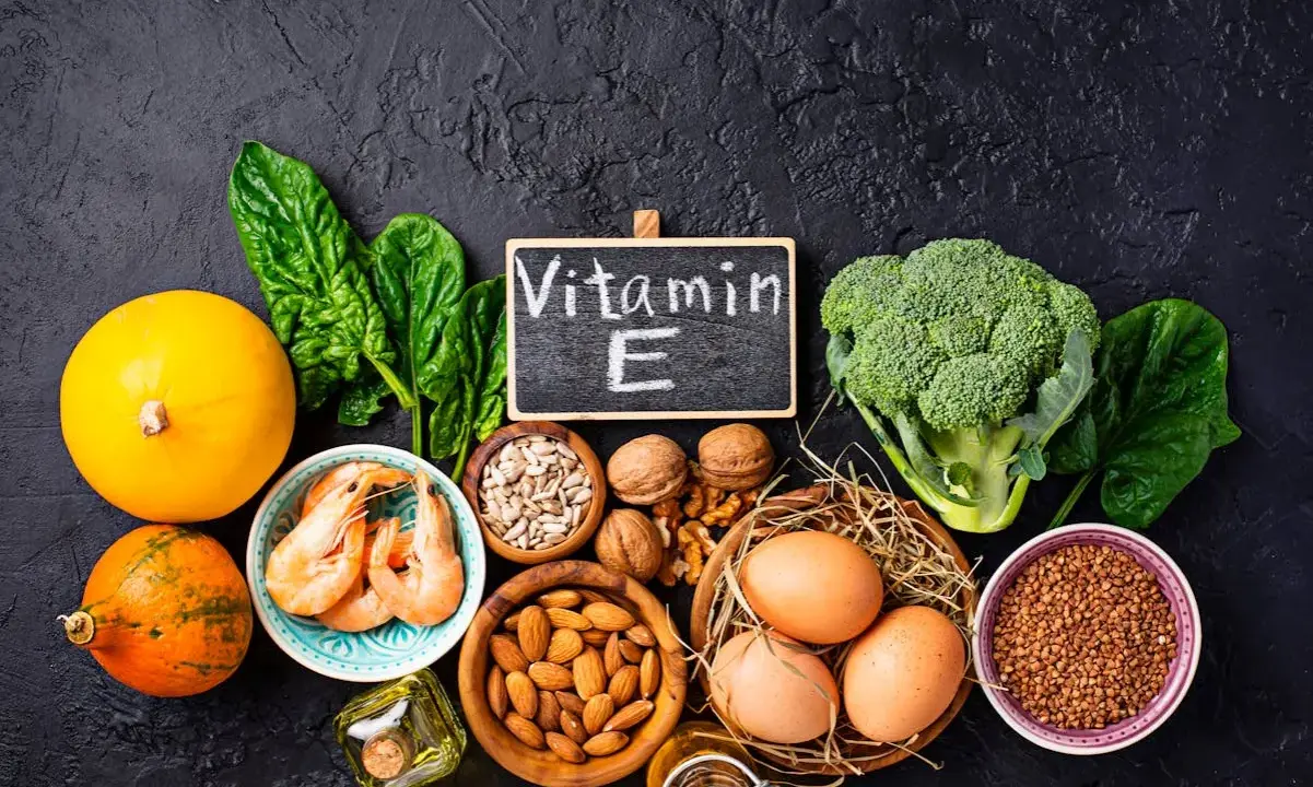 Assortiment d'aliments riches en vitamine E : courges, épinards, crevettes, noix, amandes, graines de tournesol, œufs, brocolis et sarrasin.