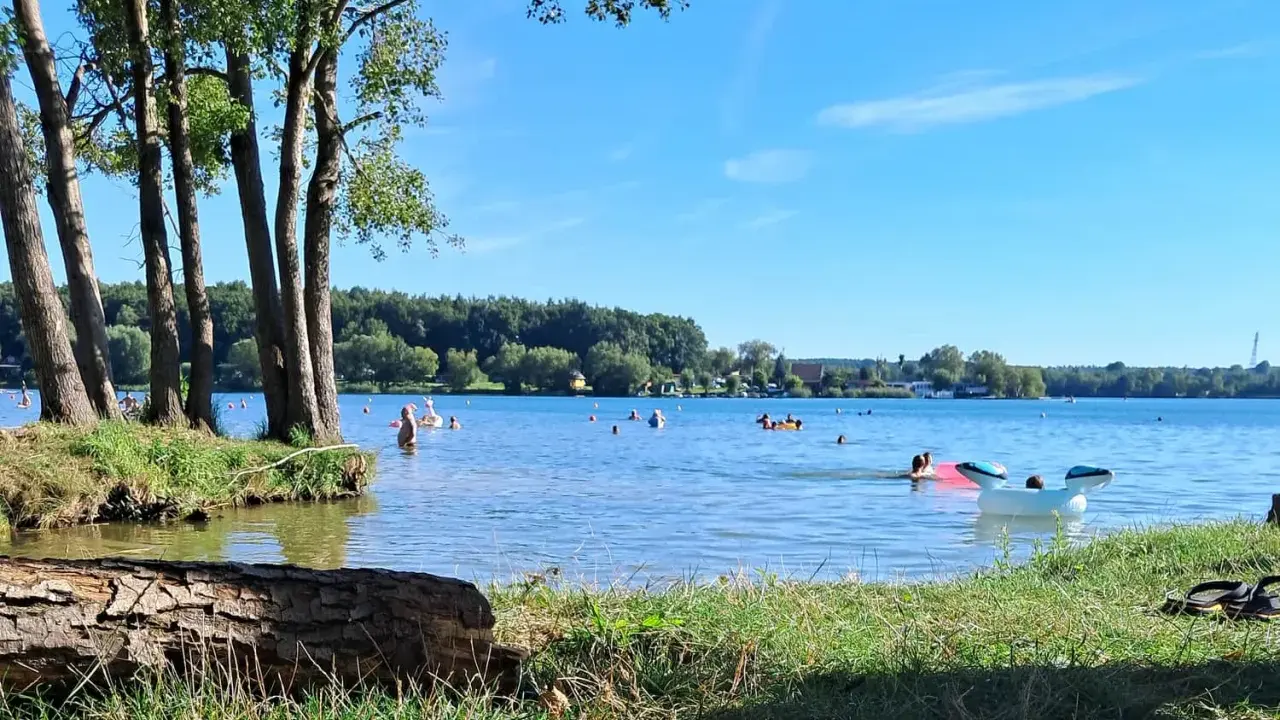 Słoneczny dzień nad jeziorem Pławniowice. Ludzie kąpią się i relaksują na dmuchanych zabawkach.